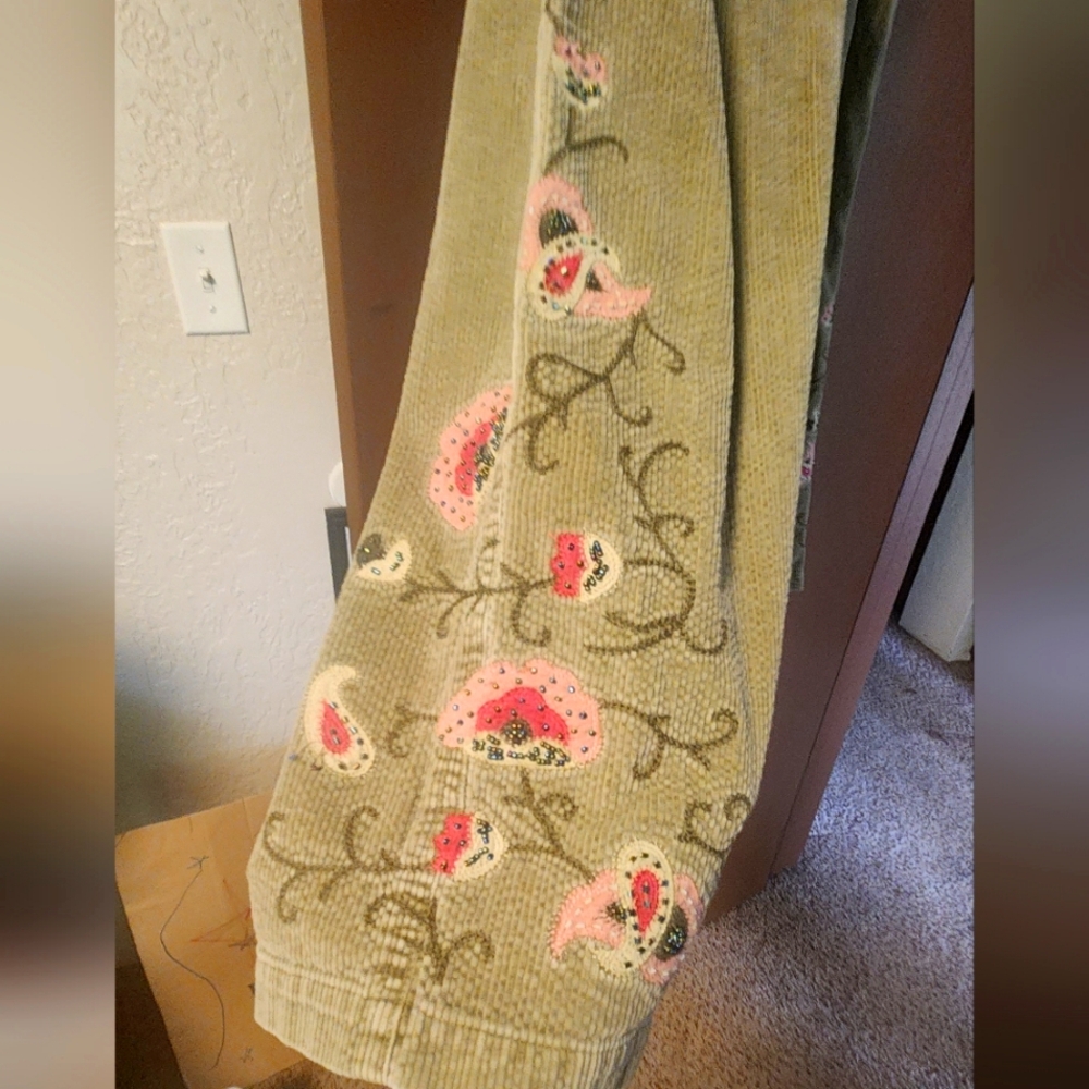 Wide leg corduroy slacks with decorative applique on legs.